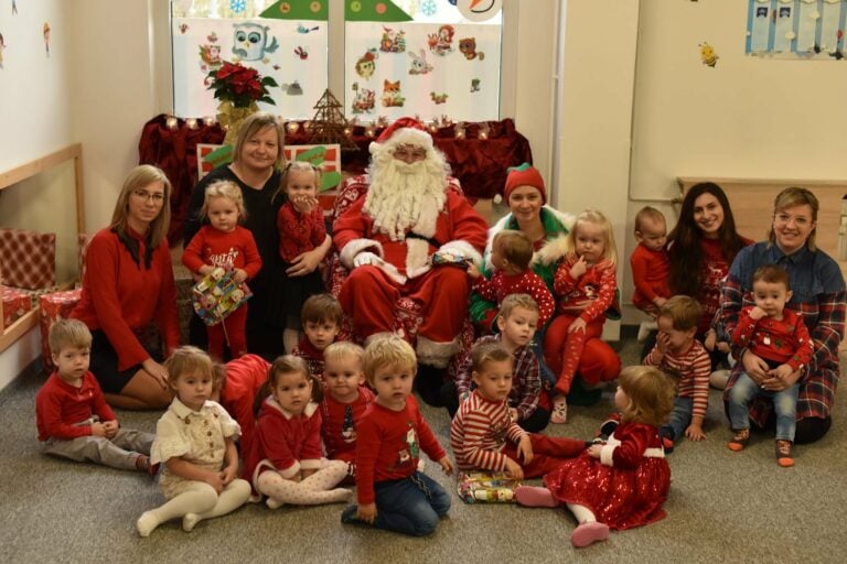 Wizyta Mikołaja w przedszkolu, dzieci razem z Mikołajem i Elfem pozują do zdjęcia.