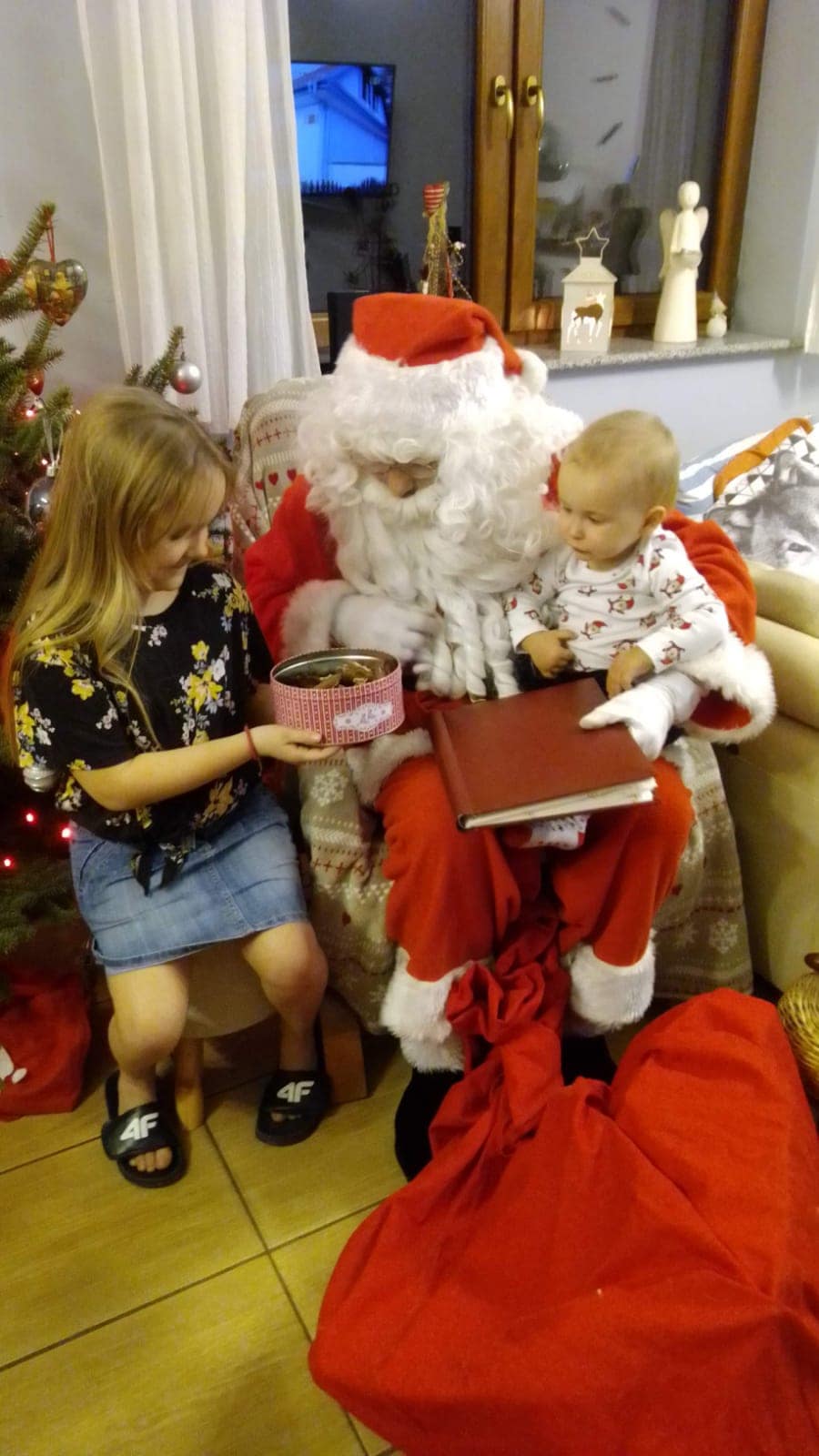 Wizyta Świętego Mikołaja w domu, Mikołaj wręcza prezenty dzieciom.
